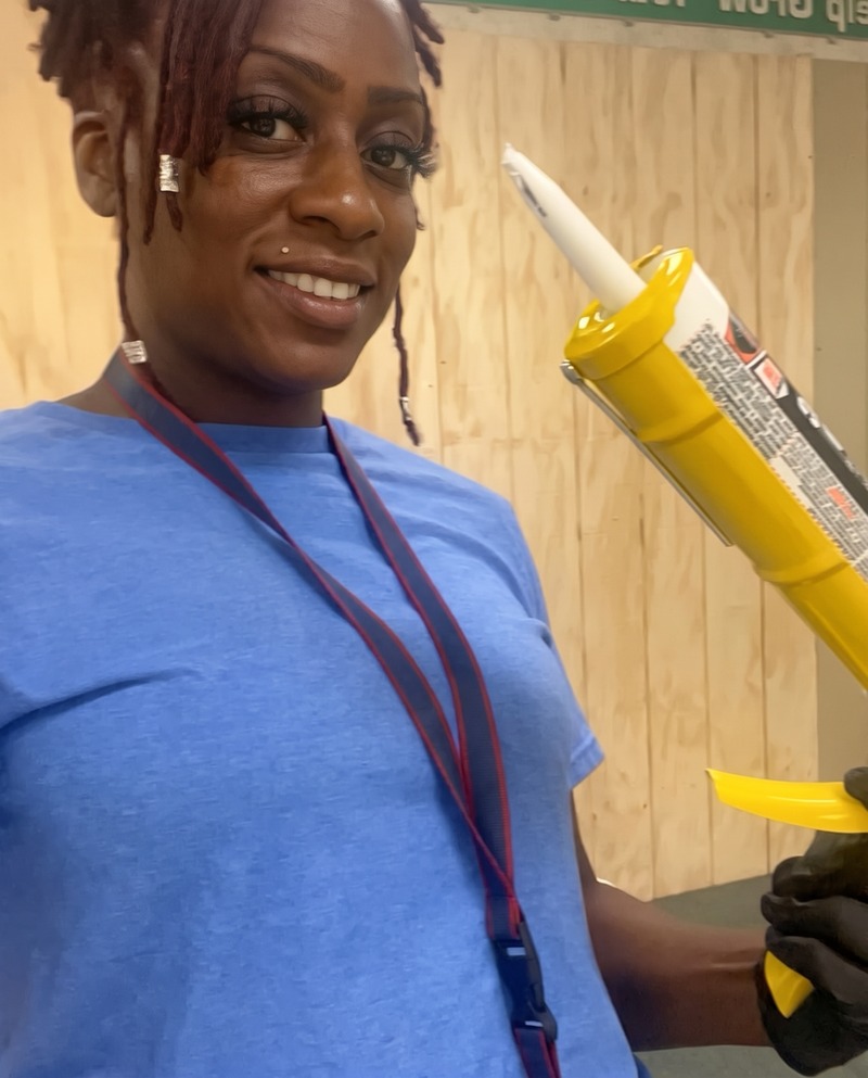 Janay holding a caulk gun at her painting training